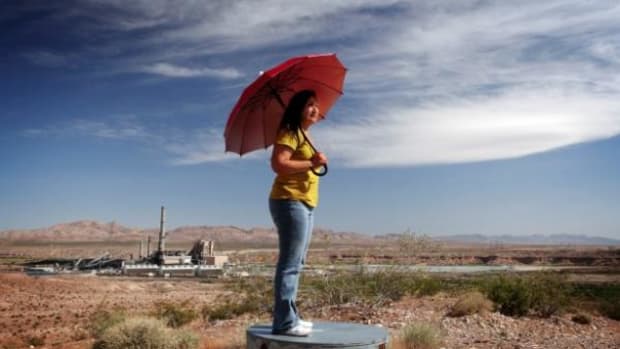 Moapa Paiute Vickie Simmons, in the film An Ill Wind, holds a virtually useless umbrella to protect her from coal power plant dust storms that make her heart race.