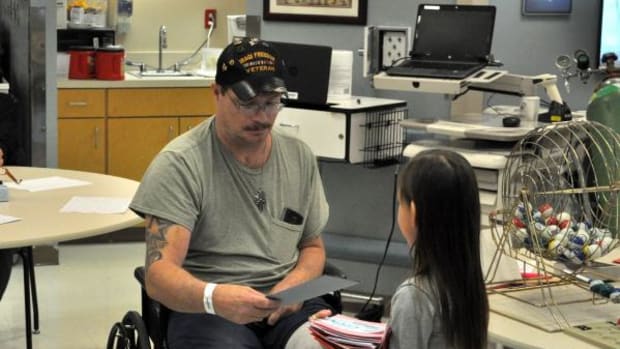 Military veteran Thomas Lynch receives a handmade Valentine’s Day card from Cherokee Immersion Charter School kindergarten student Dayci Starr.