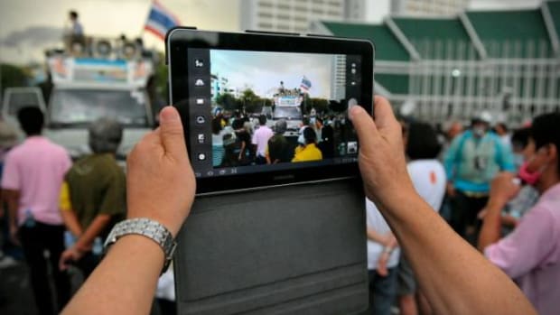 This image from November 24, 2012 shows a protester uses a tablet to photograph a rally on Makhawan Bridge in Bangkok, Thailand, organized by the nationalist Pitak Siam group. People everywhere, including journalists are using smartphones and tablets to report on events.