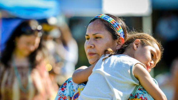 Tired from a long, fun weekend, Tayrn Walking Eagle-Mesteth carries her sleepy child at the Mother's Day pow wow in Canton, GA. Amy Morris