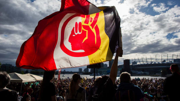 A woman silhouetted holds a flag of the American Indian Movement during a protest against the Kinder Morgan's Trans Mountain pipeline expansion, in Vancouver, British Columbia, Tuesday, May 29, 2018. Canada's federal government said Tuesday it is buying the controversial pipeline from the Alberta oil sands to the Pacific Coast to ensure it gets built. (Darryl Dyck/The Canadian Press via AP)