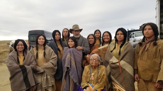 Tom Hanks (hat) gets his picture with Dorothy WhiteHorse (sitting) and the Kiowa cast of “News of the World.” (Photo by Lynda DeLaune via Gaylord News)