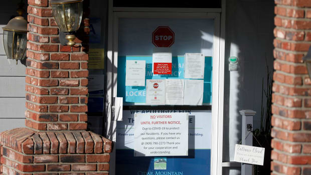 Warning notices are posted on a door at an entrance to the Cedar Mountain Post Acute nursing facility in Yucaipa, Calif., Wednesday, April 1, 2020. The Southern California nursing home has been hit hard by the coronavirus, with more than 50 residents infected, a troubling development amid cautious optimism that cases in the state may peak more slowly than expected. (AP Photo/Chris Carlson)