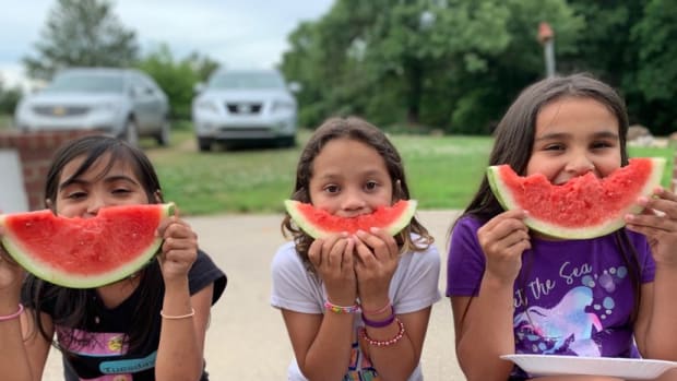Kim Duncan’s three adopted daughters, from left, Shalyn, Shyanne and Shelbi, sit smiling with their watermelon in the summer heat, September 2021. (Courtesy photo)