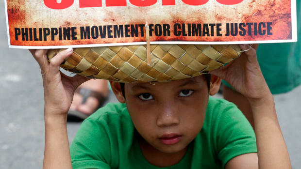 FILE - A boy holds a traditional bag with a message during a rally leading to the Presidential Palace to call on Philippine President Benigno Aquino III to focus on "climate justice" when he speaks before the UN Climate Change Summit in the United States late this month, Sept. 12, 2014, in Manila, Philippines. The overarching phrase that dominates Glasgow climate talks is simply a number: 1.5. (AP Photo/Bullit Marquez, File)