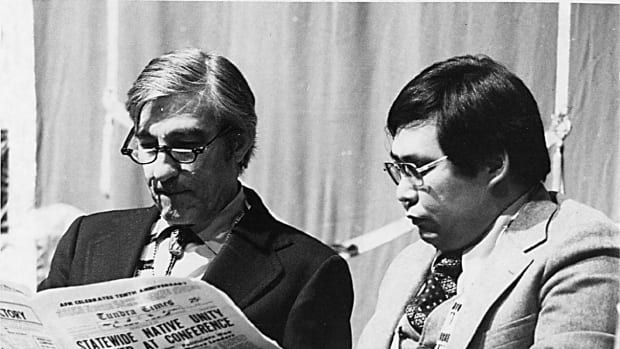 Sam Kito and Stewart Udall looking at newspaper with the headline, "Statewide Native Unity Achieved at Conference."