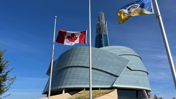 Flags fly at half-staff at the Canadian Museum for Human Rights in Winnipeg, Manitoba, as they have at all government buildings for much of 2021, to acknowledge the discovery of hundreds of unmarked graves outside the Kamloops Indian Residential School. (Photo by Miles Morrisseau for Indian Country Today)
