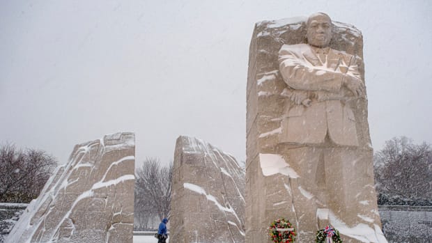 A visitor walks through the Martin Luther King, Jr. Memorial as a winter storm blows through the Washington area, Sunday, Jan. 16, 2022. Ceremonies scheduled for the site on Monday, to mark the Martin Luther King, Jr. national holiday have been canceled because of the weather. (AP Photo/J. David Ake)