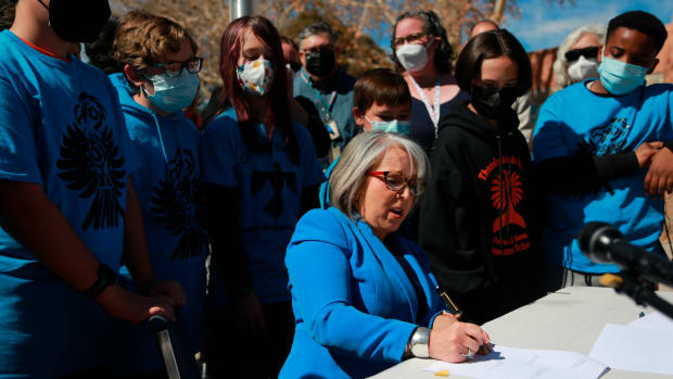 FILE- New Mexico Gov. Michelle Lujan Grisham signs one of a suite of education bills that will increase teacher salaries and benefits on Tuesday, March 1, 2022, in Santa Fe, N.M. On Thursday, March 3, 2022, Grisham signed a bill, sponsored by state Rep. Derrick Lente, of the Sandia Pueblo, that will set a minimum salary for teachers certified to teach eight tribal languages taught in public schools and spoken by members of the state's 23 tribes and pueblos. (AP Photo/Cedar Attanasio, File)