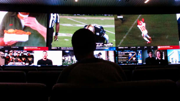 In this Nov. 20, 2018 photo, a customer watches video screens at a sportsbook in Atlantic City, N.J. On Thursday, March 11, 2021, BetMGM and Buffalo Wild Wings launched a program where special sports betting products are offered to customers at one of the chain's restaurants in New Jersey, Colorado, Indiana, Iowa, Tennessee and West Virginia. (AP Photo/Wayne Parry)