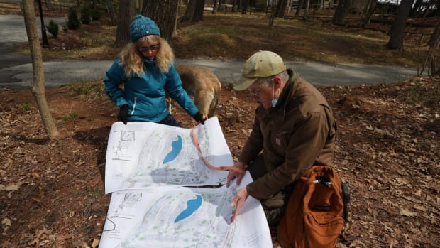 Belle Ragins and Erik Thelen, who live near the site of Kohler Co.’s proposed golf course in Sheboygan, Wis., examine a map prepared by environmental engineer Roger Miller, who chairs the town of Wilson Plan Commission. The map overlays the project with present lake levels, showing several planned features under water due to erosion and fluctuating water levels along Lake Michigan’s shoreline. Photo taken April 27, 2021. (Photo by Dee J. Hall, Wisconsin Watch)