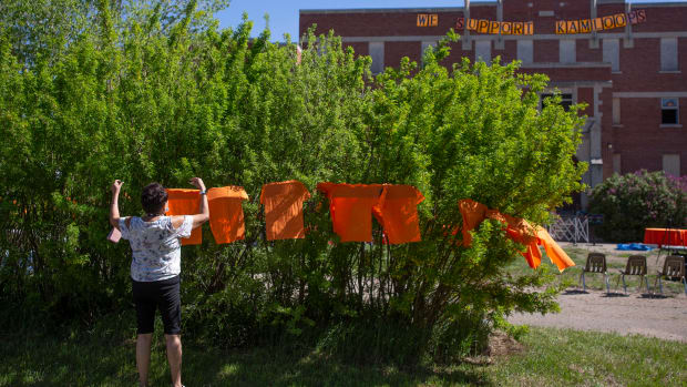 Volunteers put up orange shirts before a press conference and prayer vigil at the former Muscowequan Indian Residential School, one of the last residential schools to close its doors in Canada in 1997 and the last fully intact residential school still standing in Saskatchewan at Muskowekwan First Nation, Saskatchewan, on Tuesday, June 1, 2021. The vigil was in response to the remains of 215 children recently found at the Kamloops Indian Residential School. (Kayle Neis/The Canadian Press via AP)