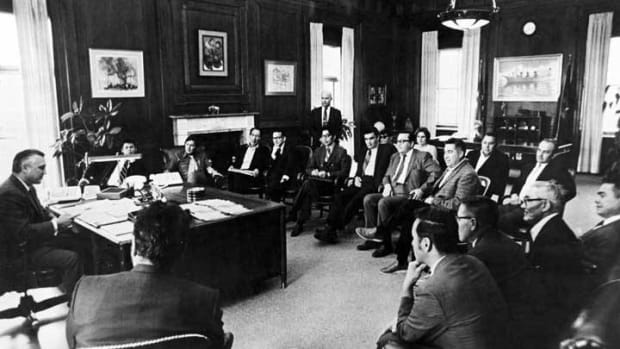 ANCSA: Meeting with Secretary of Interior Walter Hickel, Fall 1970. Sec. of Interior Walter Hickel, far left, meeting with people involved in Alaska land claims dispute. From left to right: Tim Wallis, President Fairbanks Native Association; Charles Edwardsen, Executive Director Arctic Slope Native Association; Eben Hopson, Emil Notti; Attorney Barry Jackson (standing); State Senator William Hensley; and Alfred Ketzler. Farthest back on the right are State Senator Ray Christiansen and Frank Degnan. John Borbridge is seated in the foreground. (Photo courtesy of Alaska State Library Historical Collections)