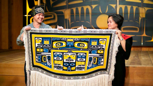 Lily Hope and Ricky Tagaban, both Tlingit, display the robe they collaborated to weave at its First Dance ceremony at the Sealaska Heritage Institute on June 22, 2020. (Photo Courtesy of Annie Bartholomew, The Juneau Empire)