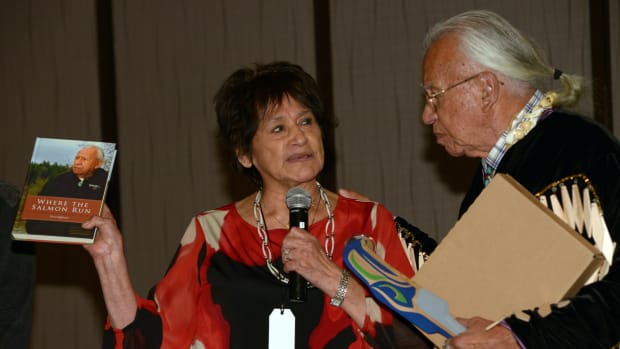 Lorraine Loomis, chairperson of the Northwest Indian Fisheries Commission, speaks with Billy Frank Jr. at his 83rd birthday party in 2014. Loomis spend more than 40 years as a fisheries commissioner, fighting for treaty fishing rights and salmon habitats, and replaced Frank as chair in 2014. Loomis died Aug. 10, 2021. Frank died in 2014.  (Photo by Debbie Preston, courtesy of the Northwest Indian Fisheries Commission)