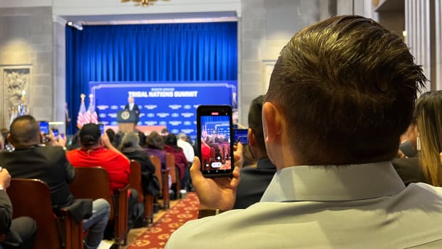 An attendee of the 2022 White House Tribal Nations Summit records President Joe Biden's remarks from his cell phone in Washington, D.C., on November 30, 2022. (Jourdan Bennett-Begaye/ICT)