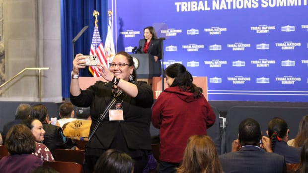 An attendee of the 2022 White House Tribal Nations Summit takes a selfie with Vice President Kamala Harris in the background in Washington, D.C., on November 30, 2022. (Jourdan Bennett-Begaye/ICT)