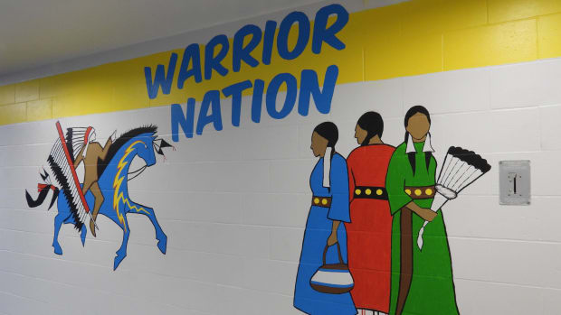 A mural in the school featuring Ozupayi (O-zoo-yaw-pi), the school’s warrior mascot, and the Three Grandmothers representing Lakota, Dakota and Natoka, the three nations of the Great Sioux Nation. (Photo by Tim Trudell for the Flatwater Free Press)