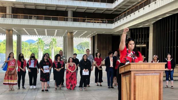 Makanalani Gomes, of AF3IRM, a feminist and decolonization organization, holds a fist in the air as she discusses a report on missing and murdered Native Hawaiian women, Wednesday, Dec. 14, 2022 in Honolulu. (AP Photo/Jennifer Sinco Kelleher)