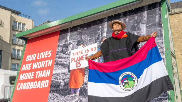 Pedro Josse Velasco Tumina, waves the flag of his indigenous people, outside the hotel where the annual general meeting of paper giant Smurfit Kappa was taking place on Friday, April 29, 2022, in Dublin, Ireland. Tumina traveled all the way from Colombia to demand the return of his ancestral lands from Smurfit Kappa, which operates paper plantations across the Central American nation. (Stephen S T Bradley/AP Images for SumOfUs)