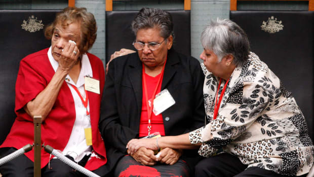 A member of Australia's Stolen Generation wipes away tear in this file photo from 2008 as Australia's then-Prime Minister Kevin Rudd apologizes to Indigenous people. The apology was directed at tens of thousands of Aborigines forcibly taken from their families as children under now-abandoned assimilation policies. As of November 2022, two Australian states are still considering whether or how to pay reparations for the injustice.  (AP Photo/Mark Baker, File)