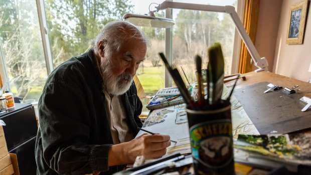 Artist Carl Gawboy works on a watercolor painting Monday, at his home studio in Two Harbors. (Derek Montgomery for MPR News)