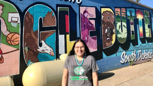 Krystal Tsosie, Diné, stands before a mural in Eagle Butte, S.D., on the Cheyenne River Reservation. Tsosie is a geneticist, epidemiologist and advocate who has begun working toward returning control of Indigenous DNA information back to individuals and tribes, an effort she calls "Databack." (Photo courtesy of Krystal Tsosie)