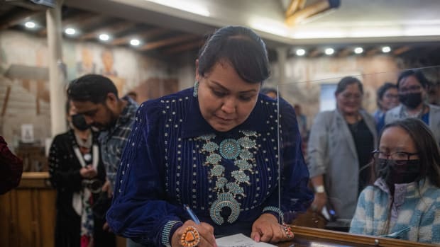 Navajo Nation Council Speaker Crystalyne Curley signs official certification while her daughter watches on. On Jan. 23, 2023 Curley was chosen to lead the Navajo Nation 25th Council in Window Rock, Ariz. (Photo by Sharon Chischilly for Source NM)