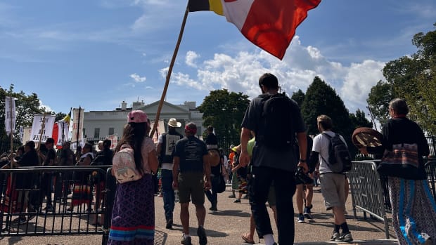 A young girl in a ribbon skirt holds an American Indian Movement flag during the Free Leonard Peltier 79th Birthday Action in front of the White House in Washington, D.C. on September 12, 2023. (Pauly Denetclaw, ICT)