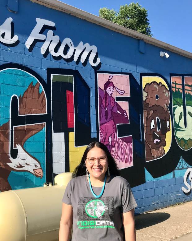 Krystal Tsosie, Diné, stands before a mural in Eagle Butte, S.D., on the Cheyenne River Reservation. Tsosie is a geneticist, epidemiologist and advocate who has begun working toward returning control of Indigenous DNA information back to individuals and tribes, an effort she calls "Databack." (Photo courtesy of Krystal Tsosie)