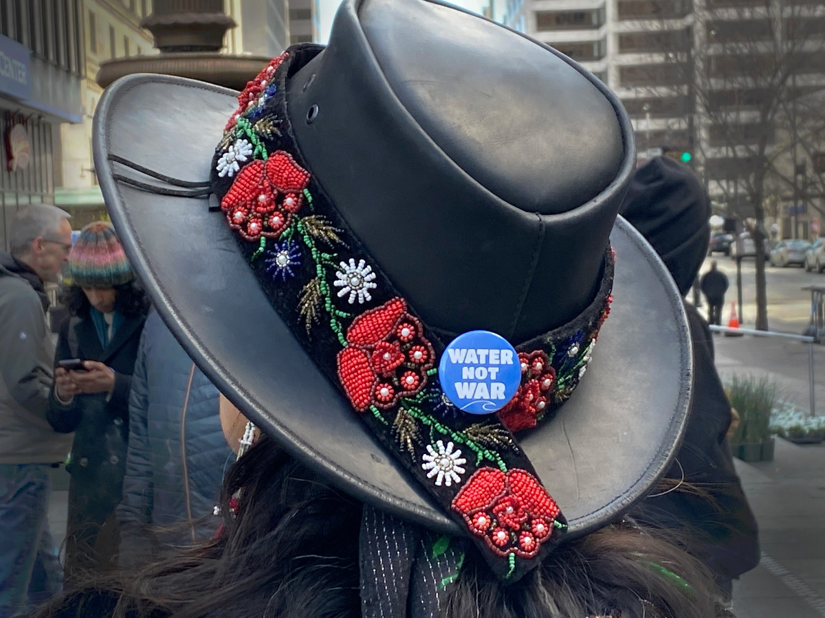 Water protector Nicole Keyawbiber wears a "Water not War" button on her hat at a rally on March 21, 2024, in Cincinnati, Ohio, supporting efforts to keep a Michigan state lawsuit seeking shutdown of Enbridge Line 5 out of federal court. (Photo by Mary Annette Pember/ICT)