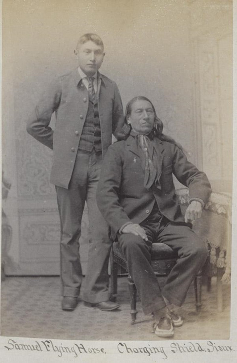 Chief Charging Shield, Oglala Sioux Tribe, seated, was photographed in 1892 with an Oglala Sioux student, Samuel Flying Horse, at the Carlisle Indian Industrial School. The chief had traveled to the school to visit his sick daughter, Fannie Charging Shield, who died March 7, 1892, of consumption while he was there. Flying Horse died the following year, also from consumption. Fannie, Samuel and another Oglala student, James Cornman, were disinterred in September 2024 and their remains returned to Pine Ridge for reburial. (Historic photo via Cumberland County Historical Society)