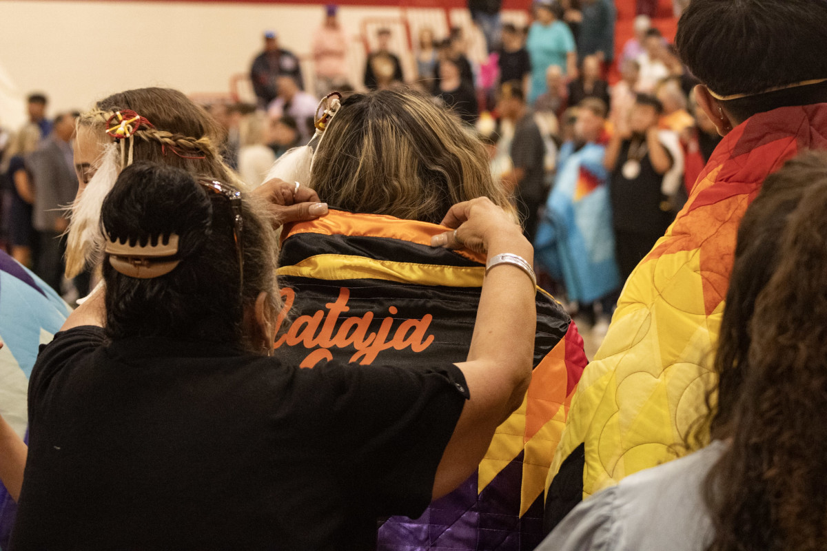 A Native graduate is wrapped in a star quilt during the May 22 feather-tying ceremony at Central High School in Rapid City. (Photo by Amelia Schafer, ICT/Rapid City Journal)