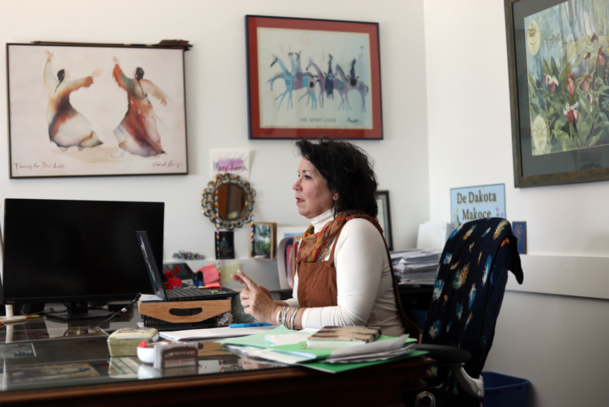 Minnesota State Sen. Mary Kunesh sits at her desk in the Minnesota Senate building. Her walls are decorated with art celebrating Native culture, including a sign that says “De Dakota Makoçe,” which means “This is our Dakota land.” (Devanie Andre, special to ICT)