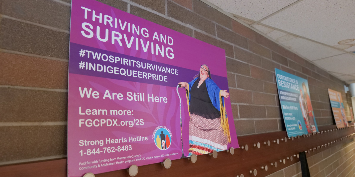 Poster boards of Two Spirit and Indiqueer individuals, like this one with Shilo George, Southern Cheyenne and Arapaho descent, were set up around the common areas of Barbie's Village on Sept. 14, 2024. George is an artist and co-host of the “Your Two-Spirit Aunties” podcast. (Photo by Jarrette Werk Underscore Native News / Report for America)