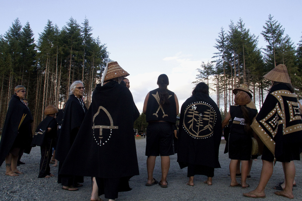 Members of the Chinook canoe family wait for their turn during Protocol held after the annual Tribal Canoe Journey, in Puyallup. Dancing is a vital expression of Chinook culture, reflecting the deep relationship with the land that teaches and remembers who they are. This spiritual connection to their ancestors is woven into the fabric of their traditions and regalia, honoring the land as both mentor and custodian.  (Photo by Amiran White)
