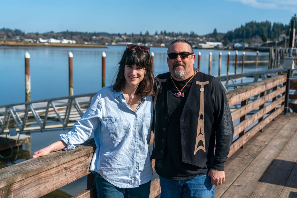 Chinook Indian Nation Chairman Tony Johnson and U.S. Representative Marie Gluesenkamp Perez stand side by side on a wooden pier in South Bend, Washington, during a March 2023 visit related to a federal recognition bill.