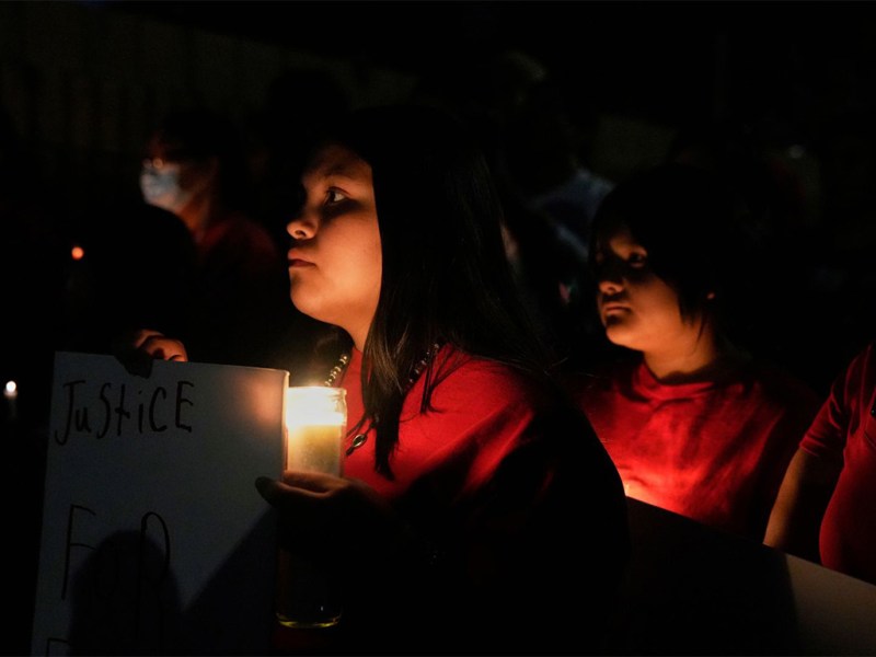 People hold candles and signs during a nighttime vigil in Mesa, Arizona, on March 6, 2025, honoring slain Native American teen Emily Pike.