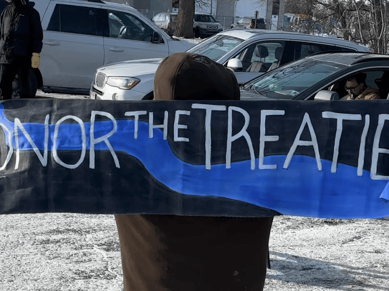 Young person holds up sign that says Honor the Treaties