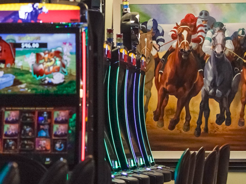 Casino with slot machines and mural of horse racing on wall in background